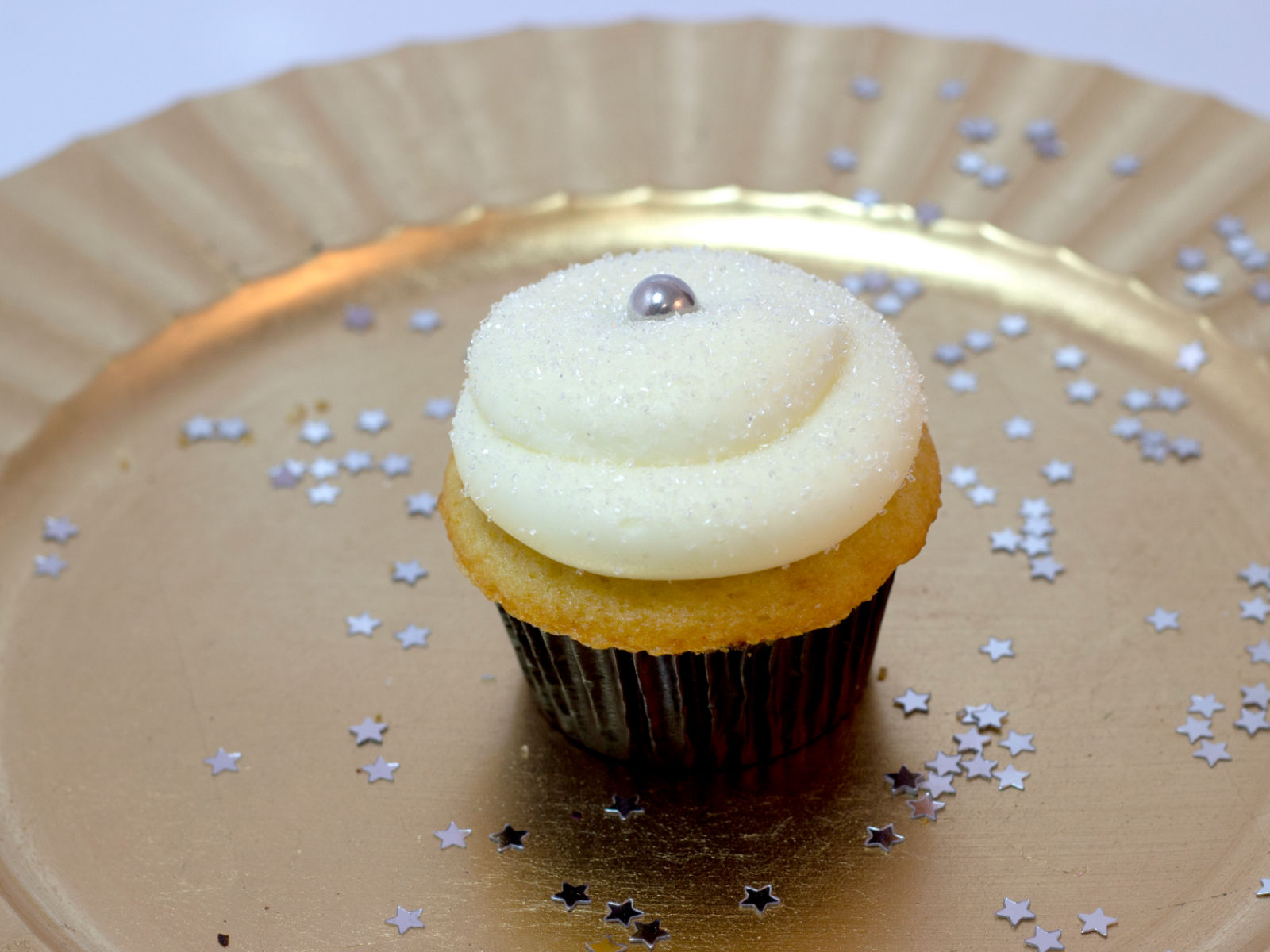 Champagne cupcake with confetti on a gold plate